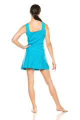 a young barefeet happy woman in a short blue dress posing on white background. Backview