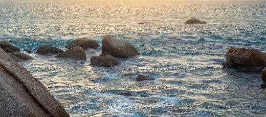 Panorama of the sea with waves crashing against the rocks at sunset. Seascape.
