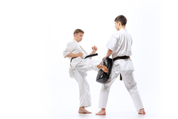 Two athletes, karate-do fighters in doboks practicing karate isolated on white background. Concept of sport, education, skills, martial arts, healthy lifestyle © master1305