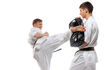 Two athletes, karate-do fighters in doboks practicing karate isolated on white background. Concept...