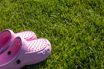 Pink comfortable flip-flops on a green grass. Text space
