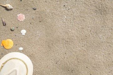 Hat and seashells on a sand. Top view, copy space