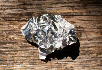 aluminum foil wrap without chocolate candy on a wooden background. Texture of used crumpled...