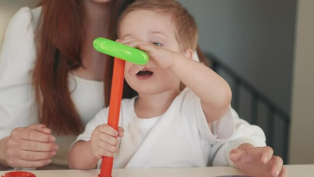the child collects a toy pyramid. mom plays with son at home happy family. development of fine motor skills in a fun newborn child. happy family mom and baby play pyramid game. preschool education