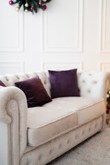 White Chesterfield Sofa with Purple Cushions in Classic White Interior. Christmas Interior in Studio