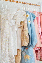 Clothing Rack with children's outfits close up. Home kids wardrobe. Nursery Storage Ideas. Baby Girl Clothes.