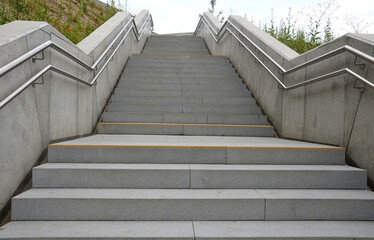 a staircase with concrete sides at a public building. the safe staircase has two handrails, one...