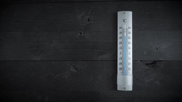 Thermometer on a black wooden table show increasing temperature,
