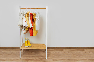 Wooden Clothing Rack with children's autumn outfits. Dresses, sweaters and jacket in kids room....