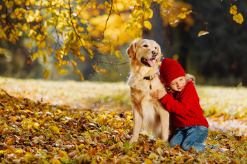 Friendly relationship between child and dog. Warm colors of autumn in the park.