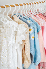 Clothing Rack with children's outfits close up. Home kids wardrobe. Nursery Storage Ideas. Baby Girl Clothes.