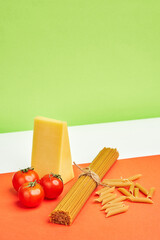 red juicy tomatoes, parmesan and whole grain spaghetti and penne against the backdrop of the colors of the italian flag. Italian products. copyspace