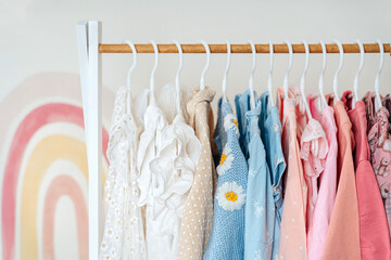 Clothing Rack with children's outfits close up. Home kids wardrobe. Nursery Storage Ideas. Baby Girl Clothes.