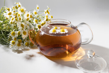 Chamomile tea in a transparent bowl on a light background