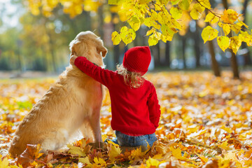 Friendly relationship between child and dog. Warm colors of autumn in the park.