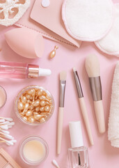 Natural skin care products and decorative cosmetics on light pink, top view