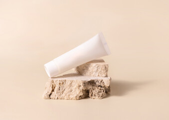 White plastic cream tube on stone on light yellow close up, Mockup