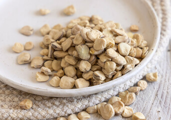Plate of raw dry Grass pea close up on wooden table. Legumes known in Italy as Cicerchia