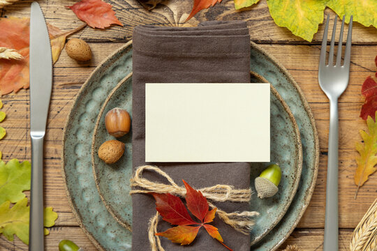Autumn rustic table setting with blank place card between colorful leaves and berries top view, mockup