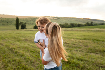 Obraz premium Portrait of a mother hugs her cute son, they look at each other and smile outside