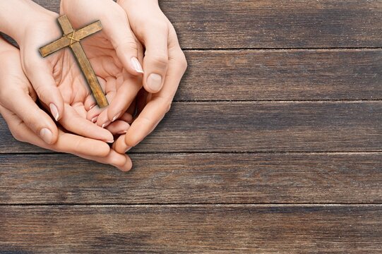 Human hand holding wooden cross crucifix. Catholicism, Christianity, Thanksgiving, Catholic and Christian faith concept.