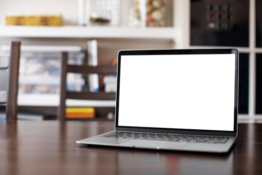 Mockup image of laptop with blank white desktop screen on a wooden table in an ordinary apartment. Laptop with blank screen for design. front view.