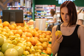 Obraz premium Young woman choosing lemon while shopping in supermarket.