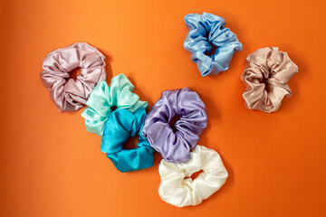 Collection of trendy silk elastic bands scrunchies on orange background. Diy accessories and hairstyles concept, luxury color