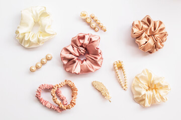 Collection of trendy silk elastic band scrunchies and pearl hair clips on white background. Diy accessories and hairstyles concept, luxury color