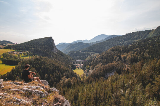 View of a tourist and the Kalte Rinne railway viaduct and a passing train in the Semmering area, Rax-Schneeberg Group in Styria, Austria