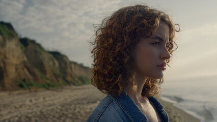 Closeup focused woman looking away on beach. Serious girl face posing at camera