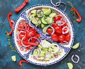 Sliced pepper, cucumber, tomatoes and onions on a ceramic menazhnitsa. Selective focus.