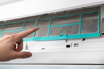 The man points with his index finger at the dirty filter of the air conditioner. Split system maintenance