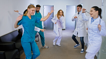 In a modern hospital corridor group of funny dancing doctors and nurses dancing and have fun