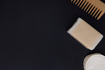 Flat lay top view soap in craft paper reusable sponges, bamboo comb on black isolate background. Concept: Zero waste eco friendly bath accessories
