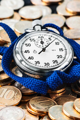 Analog stopwatch and pile of gold coins on a black background close-up. Counting time by stopwatch....