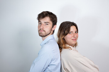 portrait d'un jeune couple de 25 ans dos à dos souriant et regardant la caméra. Isolé sur fond...
