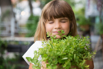 child girl holding pot with mixed green fresh aromatic herbs in garden near the house. enjoy the little things. favorite family hobby. Eco-friendly.  © ulza