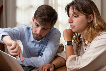 un jeune homme et une jeune femme travaillent en collaboration avec des ordinateurs portables. Deux collègues discutent au bureau du projet sur lequel ils travaillent