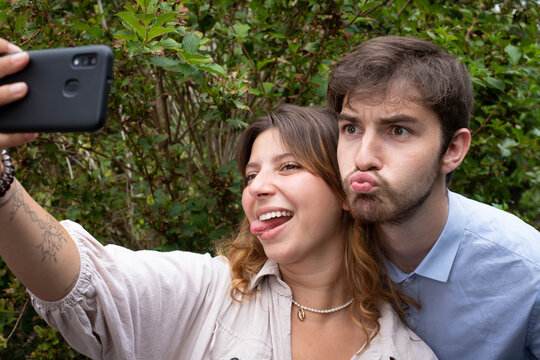 un couple d'amis fait un selfie avec un t&eacute;l&eacute;phone portable et fait des grimaces. Moment fun entre jeunes adultes.