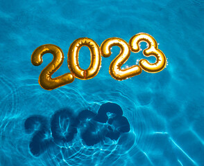 figures 2023 new year float in the blue pool in splashes of water