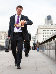 Late for Work. A smart young business man hurriedly checking the time while crossing London Bridge...