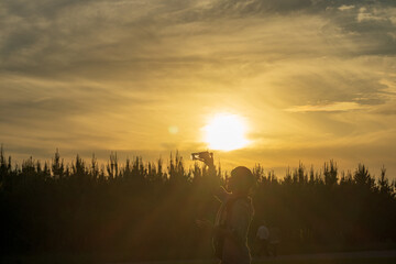 ジャグリングの練習をする少年のシルエットと夕日