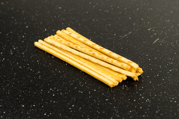 Yellow corn snack sticks top down view on a black cutting board