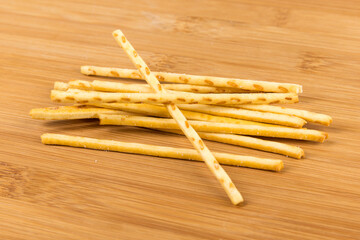 Random stack of corn snack sticks top down view on a wood cutting board