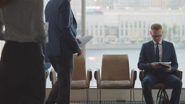 Business people sit on chairs in row waiting for job interview. Realtime