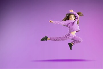 Overjoyed teen girl in fashionable clothes dance on studio background. Hobby and entertainment.