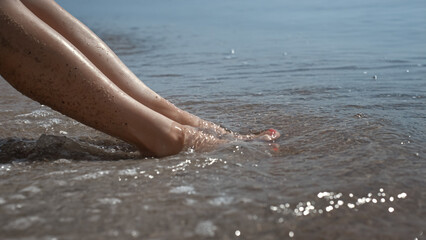 Tanned woman legs smeared beach sand on sunlight closeup. Sexy lady sunbathing.