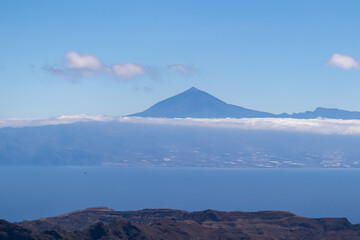 Scenic view on cloud covered volcano mountain peak Pico del Teide on Tenerife seen from Mirador Morro de Agando, La Gomera, Canary Islands, Spain, Europe. Lookout near Roque de Agando. Atlantic Ocean
