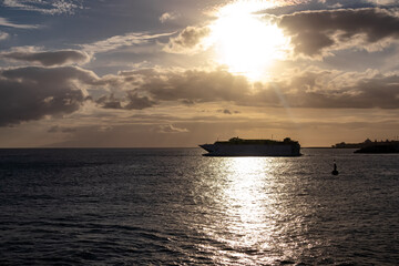 Romantic sunset seen from lookout Cypelek Los Cristianos, Tenerife, Canary Islands, Spain, Europe. Silhouette of regular ferry boat leaving from the harbour towards Island of La Gomera. Island hopping